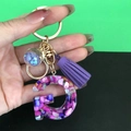 Detail of resin letter G keychain with purple tassel and star charm in gold plating - Letter G