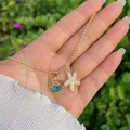 Close-up of gold beaded necklace with pearl starfish and blue crystal fish pendants - Pearl Starfish Style