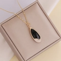 Gold chain necklace with black teardrop pendant featuring white crystals and heart detail - Black