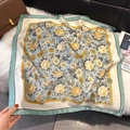 Detailed close-up of a floral satin scarf with blue and yellow botanical print on fur - Turquoise Green