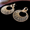 Dettaglio di grandi orecchini a cerchio dorati con texture di filo metallico avvolto - Perno in argento 925 / Oro
