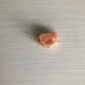 Handmade orange crystal raw stone pendant wrapped in golden wire on wood surface - Gold Wire Red Aventurine