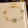 Dettaglio del bracciale dorato con pietre blu e ciondoli a farfalla e fiori - Zircone Blu (B2018)