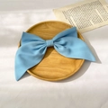 Close-up of a large light blue fabric bow hair clip placed on a rustic wooden plate - Two-Layer Bow Spring Clip / Blue