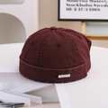 Close-up of a burgundy cotton docker hat with a metal plaque detail on a clean table - 55-58cm / Metal Label Style / Red