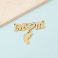 Close-up of golden MOM pendant with sparkling heart and baby feet charm on blue surface - Gold Tone MOM + 1 Foot Pendant