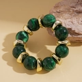 Dettaglio di perline marmorizzate verde scuro e distanziatori dorati su bracciale vintage - Verde
