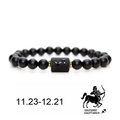 Bracelet Sagittaire en perles noires mates avec entretoises dorées et symbole sur fond blanc - Sagittaire