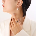 Elegante zilveren druppeloorbellen en vierkante tijgeroog ring op een model in een wit pak - Zilver