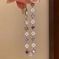 Silver bracelet featuring purple round gemstones and white floral motifs held by hand - Purple Flower