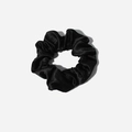 Detail of the soft satin fabric texture and pleated folds on a black scrunchie - Black