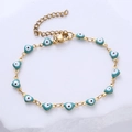 Detalle de pulsera de corazón de mal de ojo dorada con dijes de esmalte azul y cierre de langosta - Ojo Cian