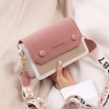 Pink and beige crossbody bag with wide embroidered strap held by a model in a wool coat - Pink