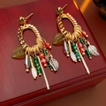 Detalle de pendientes de cadena con hojas y borlas sobre una caja de madera rústica - Poste de plata - Dorado - Verde