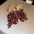 Makro-Detail von Blatt-Goldbasis und roten Trauben-Perlenquasten an Hängeohrringen - Weinrot (Silbernadel)