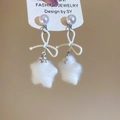 Detail of white velvet star earrings with pearl studs and bow accents on jewelry card - White