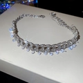 Makroaufnahme einer silbernen Quastenkette mit Zirkonia-Anhängern auf einer Geschenkbox - Silber
