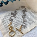 Zweifarbige Halskette mit goldenem OT-Knebelverschluss auf italienischem Buchhintergrund - Zweifarbig