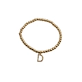 Detailed macro view of gold beaded bracelet featuring a colorful rhinestone D initial charm - Letter D