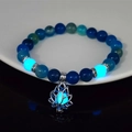 Detailed view of luminous lotus flower charm bracelet with teal beads in darkness - 8mm Natural Royal Blue Agate with Blue Light