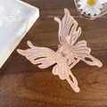 Pearlescent pink iridescent butterfly hair claw clip with cutout wings on wood surface - Large Butterfly 9cm / Iridescent Orange