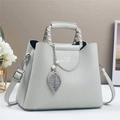 Detailed macro of mint green lychee grain leather handbag with metal leaf pendant - Gray