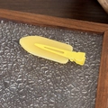 Dettaglio di un fermaglio per capelli in resina gialla opaca su vetro e legno - Piccolo Senza Tracce - Giallo Lucido