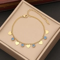 Golden stainless steel bracelet featuring blue evil eye and heart charms on jewelry box - Bracelet