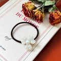 Elegante goma de pelo negra con flor de trébol en acetato blanco y perla sobre libro - Blanco Idiscente
