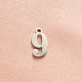 Detailed macro view of silver number nine stainless steel pendant on textured fabric - Steel Color Number 9