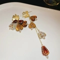 Detail view of asymmetric floral earrings with amber resin heart and long gold tassels - Coffee Gold With Silver Pin