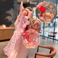 Pink sakura keychain featuring a resin rose globe and rubber handle strap with golden ring - Lanyard Style / Pink