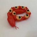 Articulated plastic toy snake in red with yellow and black eye-patterned body segments - Red