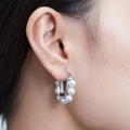Primer plano de pendientes de plata en forma de U con perlas blancas en la oreja - Color Acero