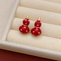 Detail van rode emaille pompoen oorbellen in een beige fluwelen juwelendoosje - Hulu Gourd Ketting Oorbellen Set (925 Zilveren Pin/Verguld)