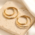 Textured gold hoop earrings with diagonal stripes on minimalist beige stone tray - Diagonal Stripe Engraved Hoop Style (E131)