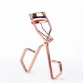 Piegaciglia in oro rosa con cuscinetti in silicone rosso e nero su sfondo bianco - Oro rosa