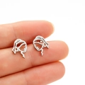 Close-up of abstract face silhouette earrings held by hand for size reference - Steel