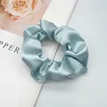 Detailed view of light blue satin scrunchie with silky texture and elegant folds - Apple Green