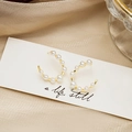 Detalle de pendientes de perlas doradas en forma de C sobre fondo de seda elegante - Hileras de Perlas Doradas Forma C