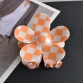 Close-up of orange and white checkerboard flower hair claw clip on fashion magazine - Orange/White Plaid Flower