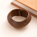 Detailed view of wide wooden bangle featuring natural wood grain on a beige surface - L413-1 Dark Coffee Spiral 3D