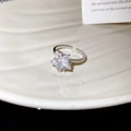 Detail van zilveren sterring met grote zirkoon en pavé-zetting op een wit bord - Witte Ster Zirkonia Stijl