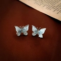 Dettaglio di orecchini a farfalla con resina marmorizzata blu e cristalli su pelle - Perno in Argento - Orecchini a Bottone con Farfalla in Cristallo Blu Chiaro