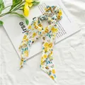 Close-up of chiffon floral scrunchie with long ribbons on a white magazine background - Yellow