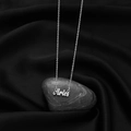 Detailed close-up of silver Aries zodiac necklace on a natural stone with black silk - Aries Steel