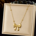 Dettaglio di una collana con ciondolo a fiocco dorato lucido in un cofanetto di seta - Stile Fiocco Lineare Semplice (N3944)