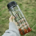 Hand holding minimalist transparent plastic water bottle with black lid and fruit - Black (My Bottle Style)