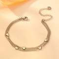 Detailed view of silver double-layer heart bracelet on a beige textured background - Silver Bracelet