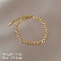 Dettaglio macro del ciondolo a trifoglio dorato su bracciale a catena in titanio - Oro